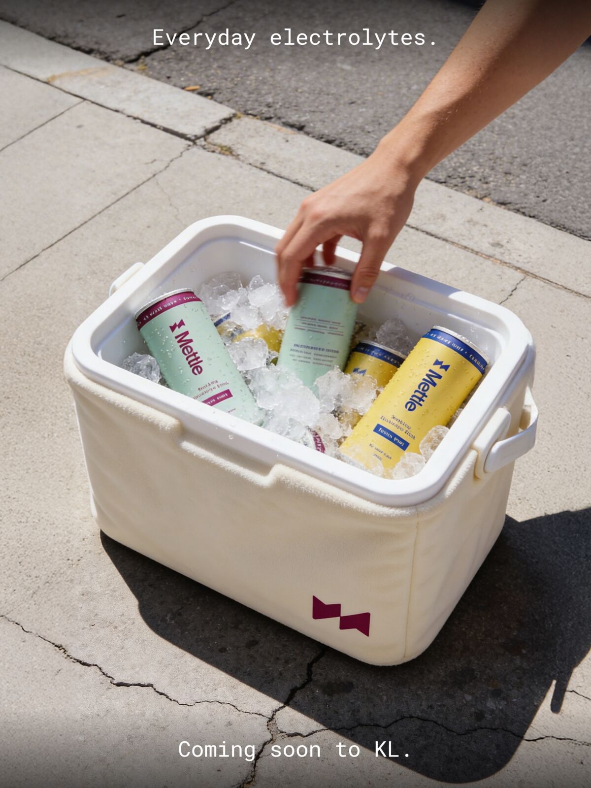 A hand taking a Mettle can from a cooler on the pavement